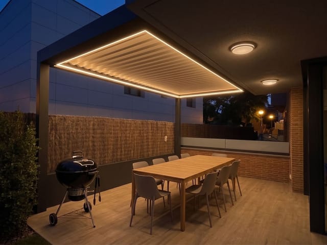Pérgola bioclimática CERCA ampliando el porche existente de una vivienda, a última hora de la tarde